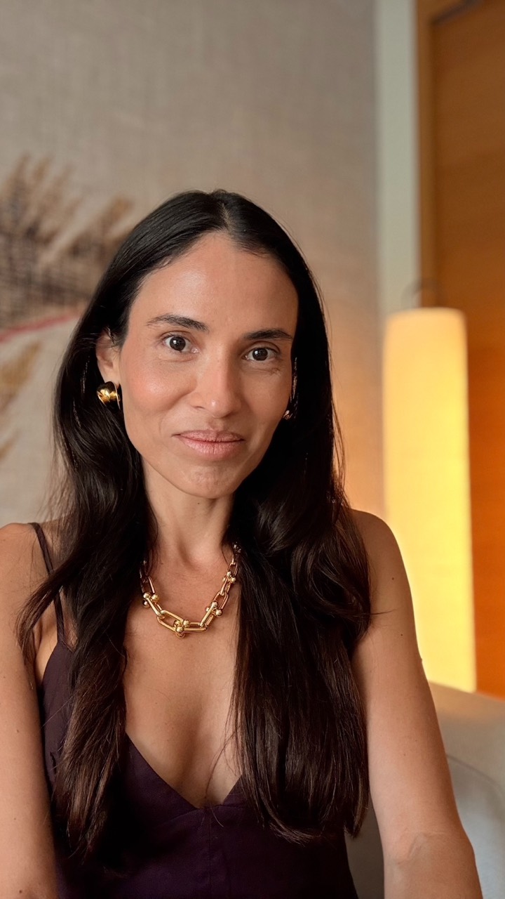 Retrato de Dani Hayoshi em ambiente interno, com cabelo longo escuro, vestido escuro e colar dourado.